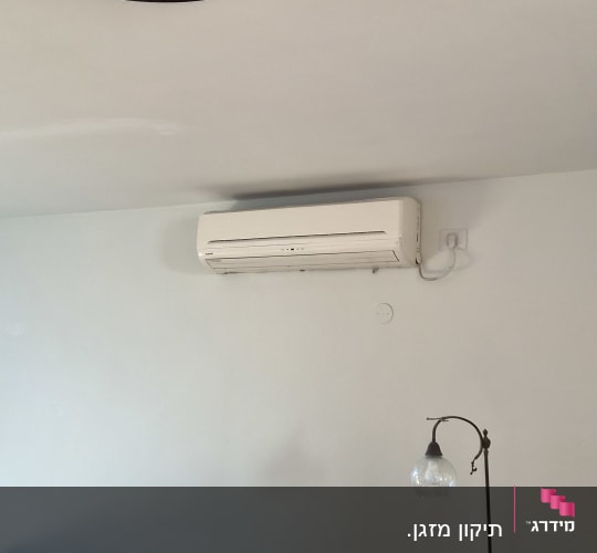 סלון עם מזגן על הקיר וספה עם כריות